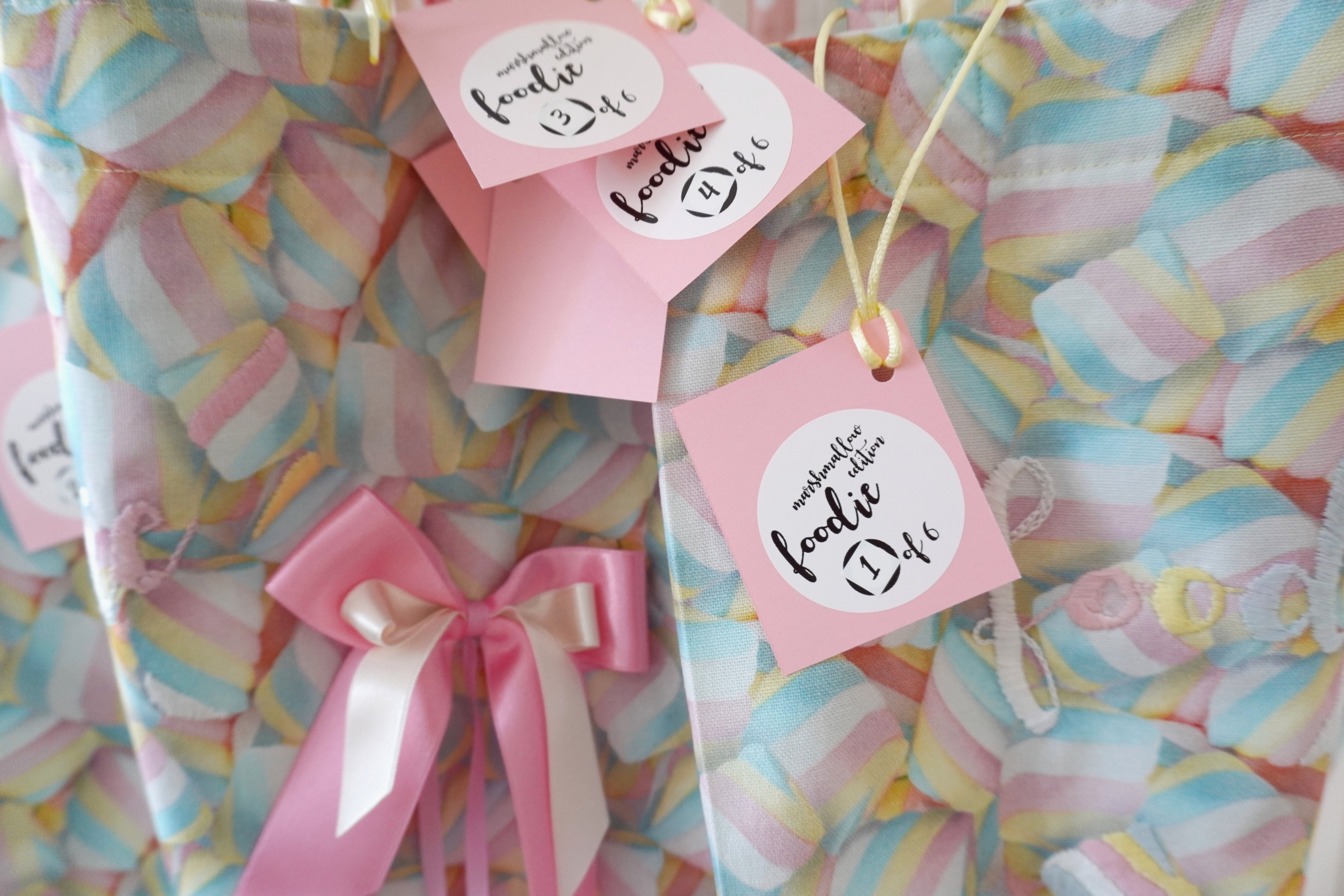 Pastel marshmallow-themed fabric with pink ribbons and foodie tags.