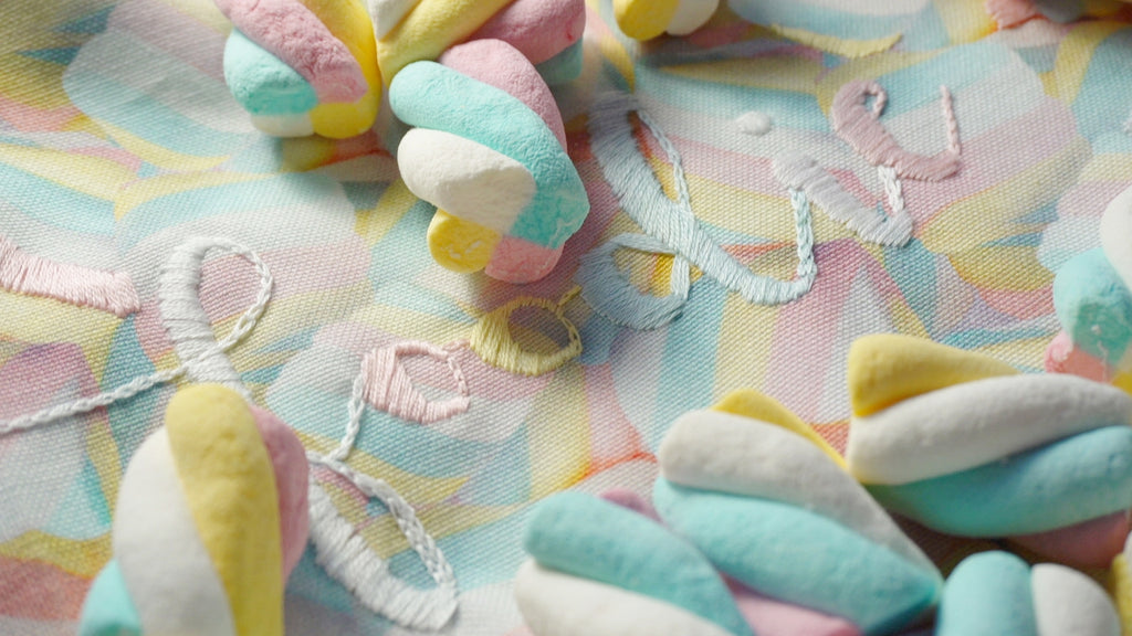 Pastel-colored marshmallows on a marshmallow patterned fabric background