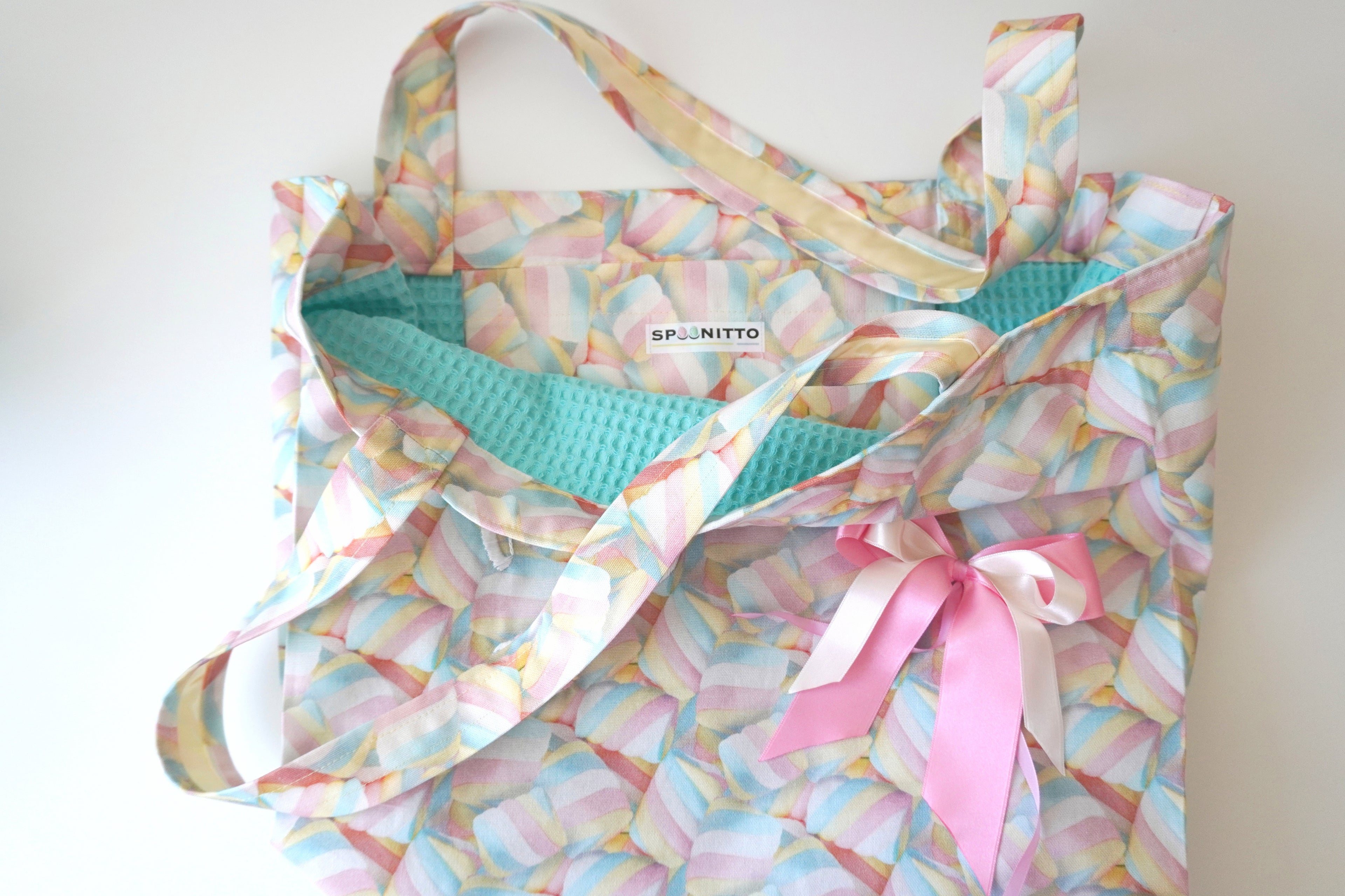 Colorful tote bag with a marshmallow pattern and a pink ribbon bow on a white background