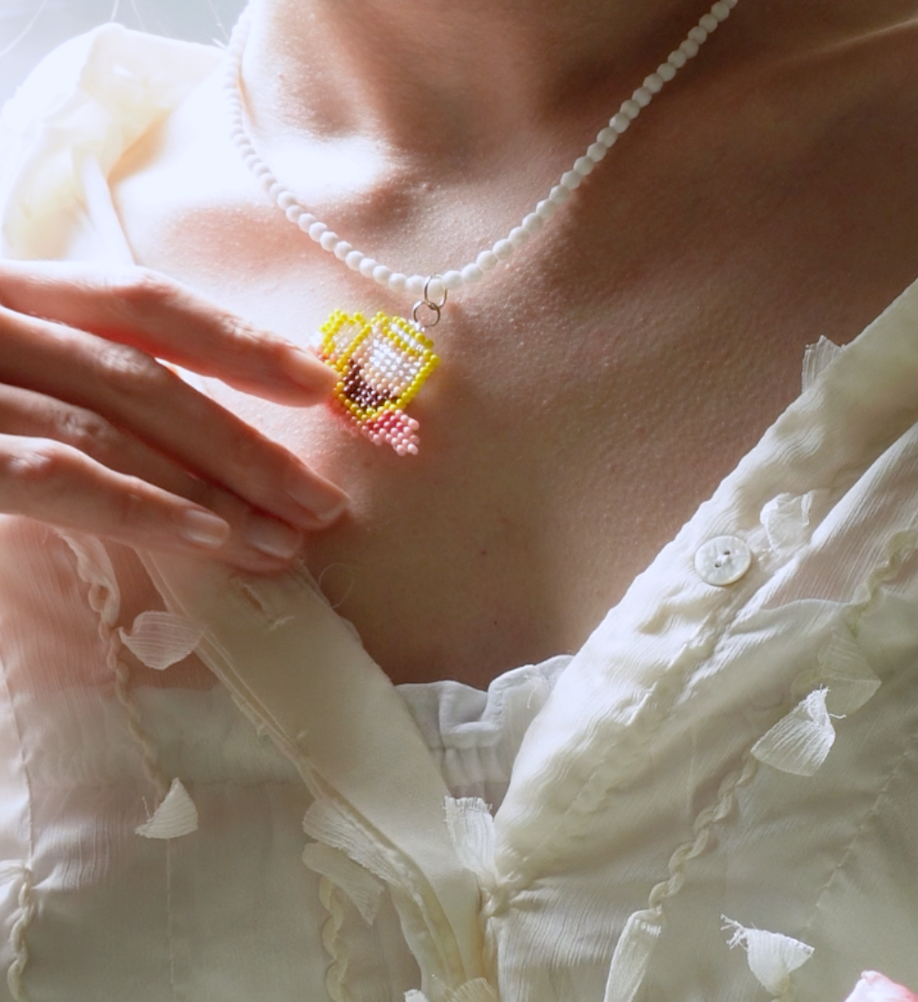 Close-up of a person wearing a white shirt with a beaded SPOONITTO brand coffee necklace.