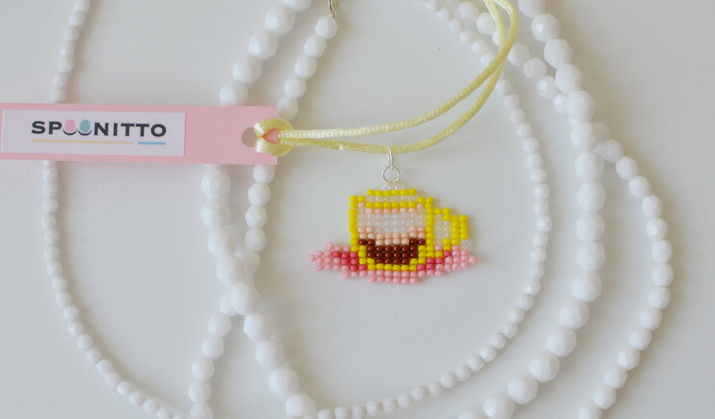 Close-up of a beaded ristretto coffee cup pendant on a white background.