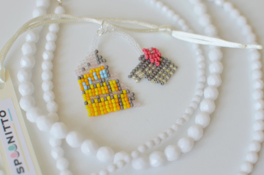 White beaded necklace with a Colosseum pendant on a white textured surface.