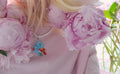person wearing beaded necklace inspired by Italian houses with geranium flowers and pink t-shirt with peony background