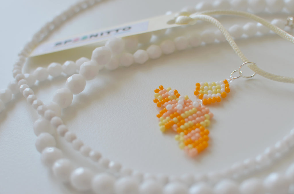 Close-up of a beaded golden cornetto pendant on a white background.