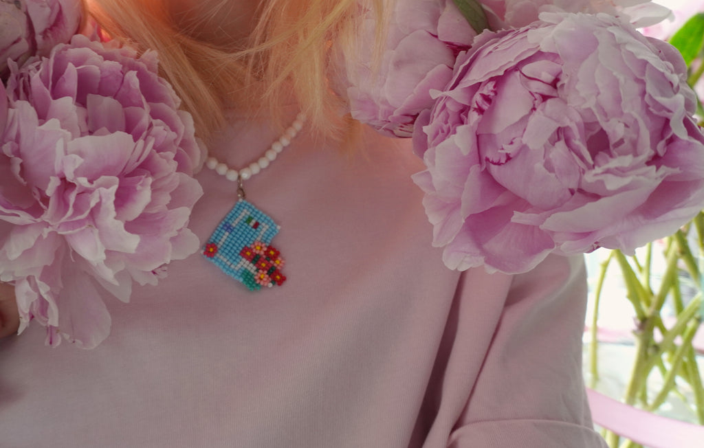 Person wearing a beaded necklace with pink flowers and Italian house front door - SPOONITTO brand