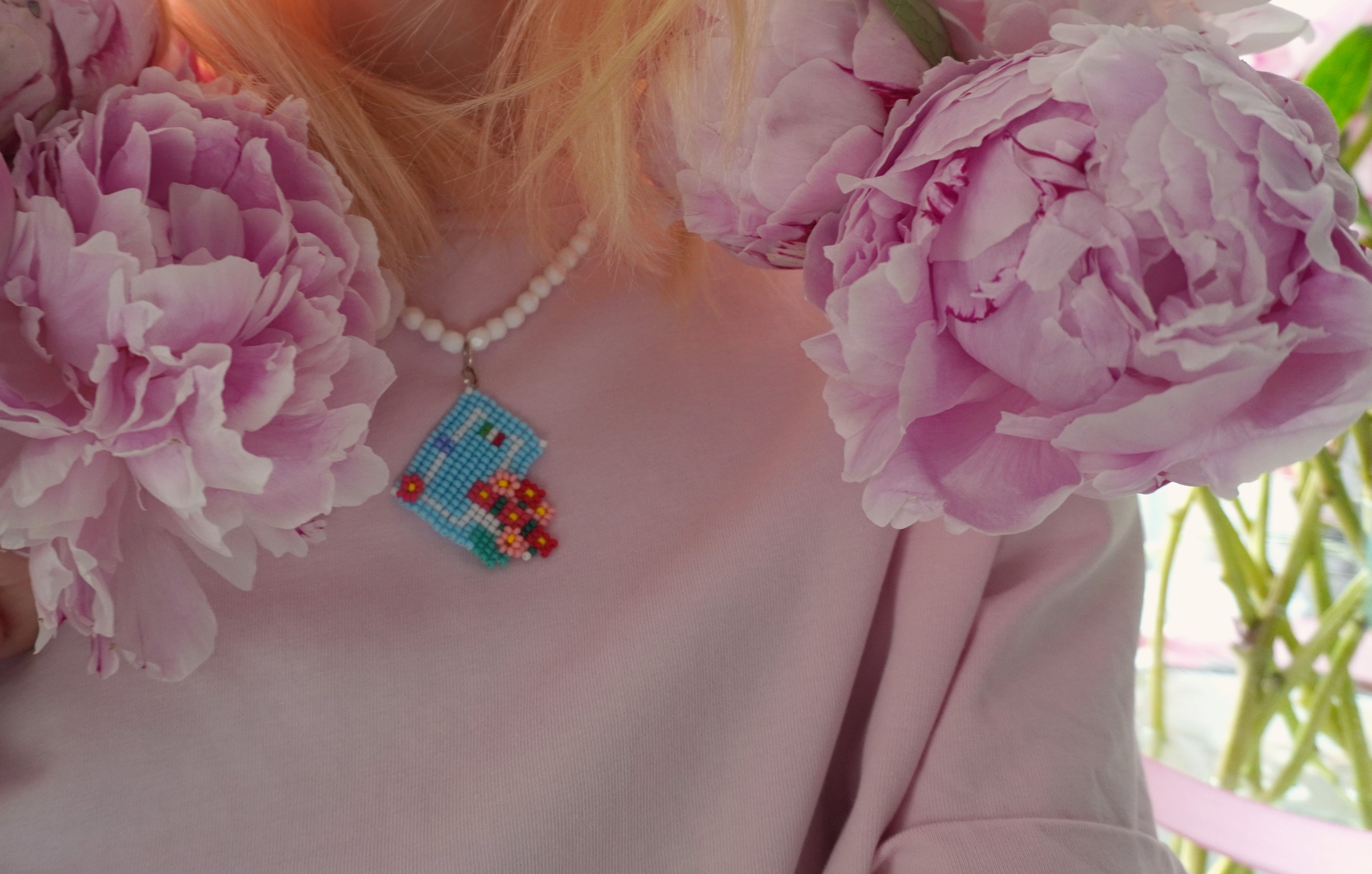 Person wearing a beaded necklace with pink flowers and Italian house front door - SPOONITTO brand