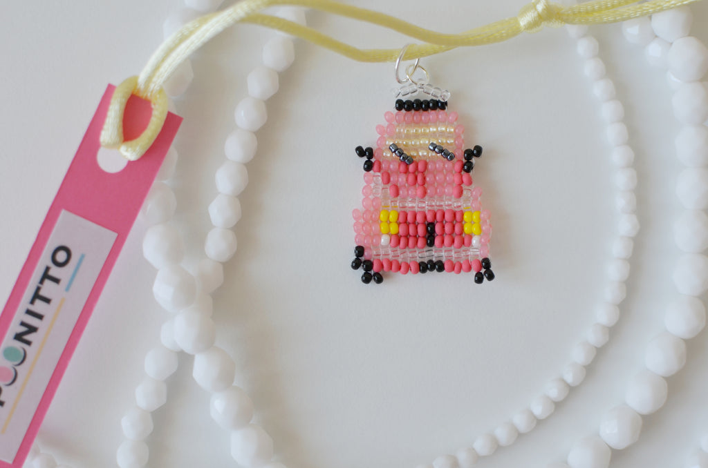 Beaded red retro car pendant on a white necklace with a SPOONITTO brand card on white background.