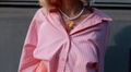 Person wearing a pink striped shirt with a white beaded necklace featuring a spaghetti pot pendant.