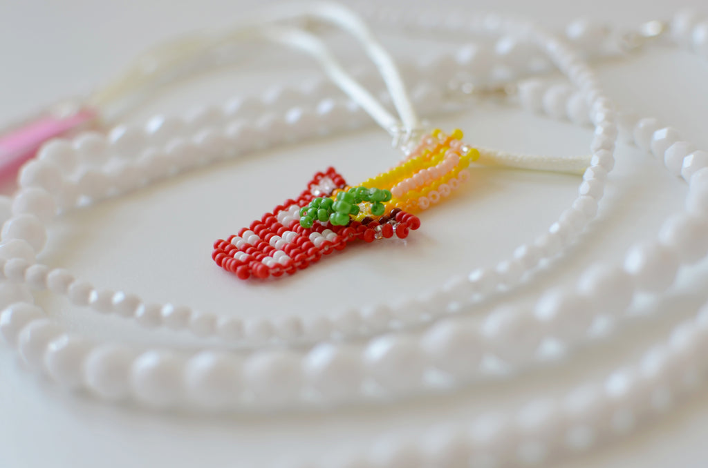 Close-up of a beaded pasta pot pendant with spaghetti and basil design.
