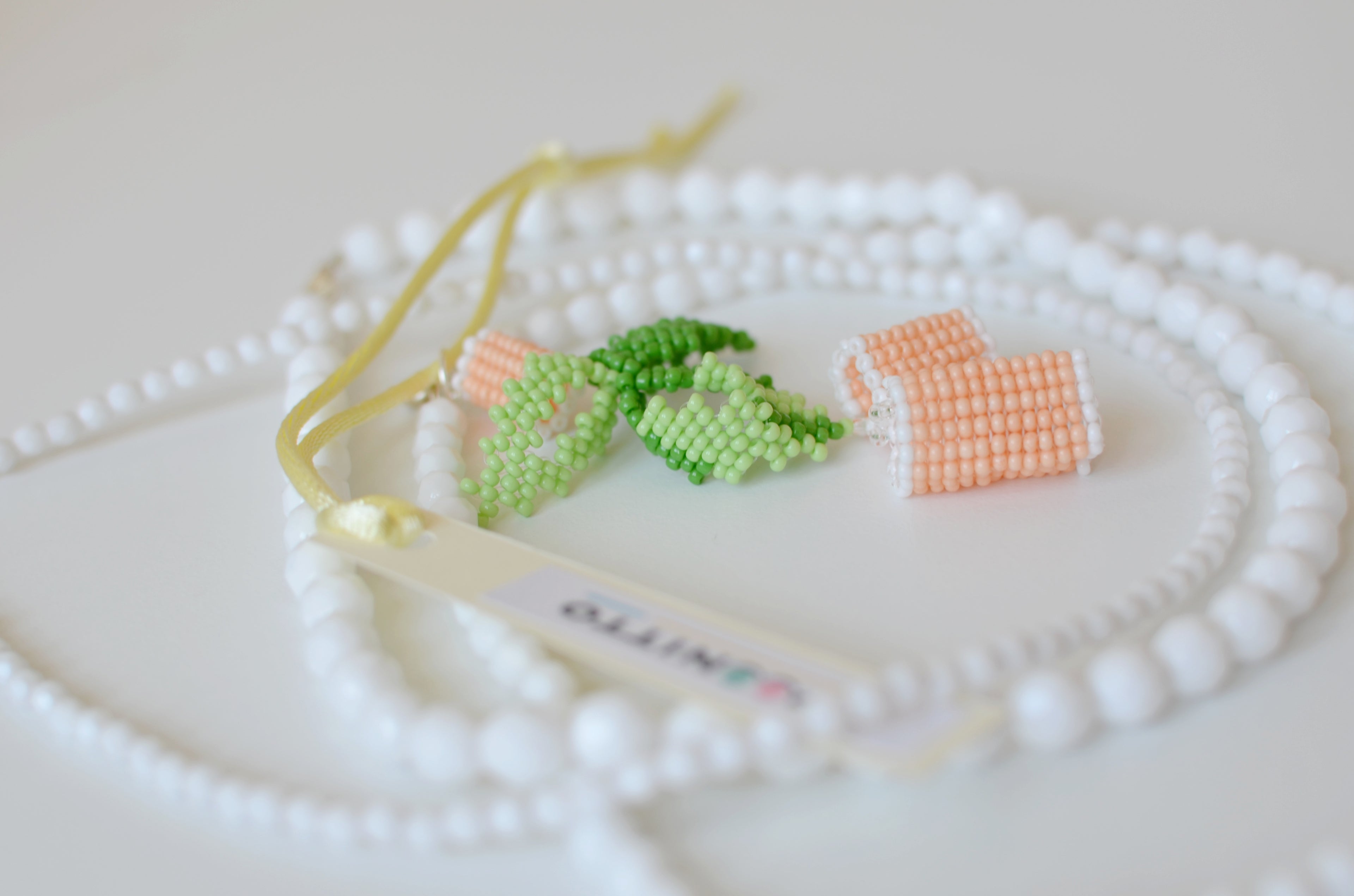 Close-up of a necklace with small green and orange beads on a white background