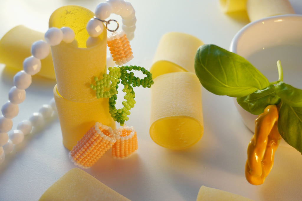 Hand-made beaded necklace inspired by Italian food with paccheri pasta and basil as a background