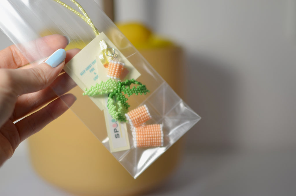 Hand holding a clear plastic bag with small pasta pendant on a light background