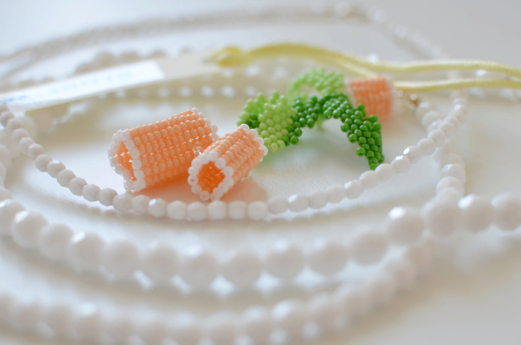 Close-up of a necklace with beige and green beads on a textured white background