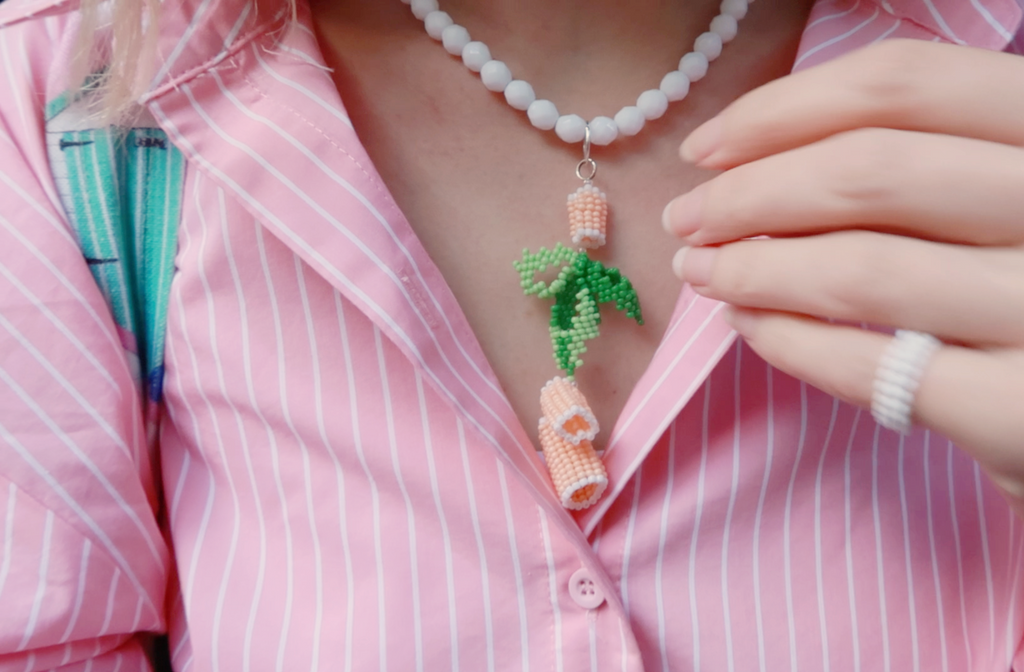 Person wearing a colorful beaded necklace inspired by food with a pink shirt