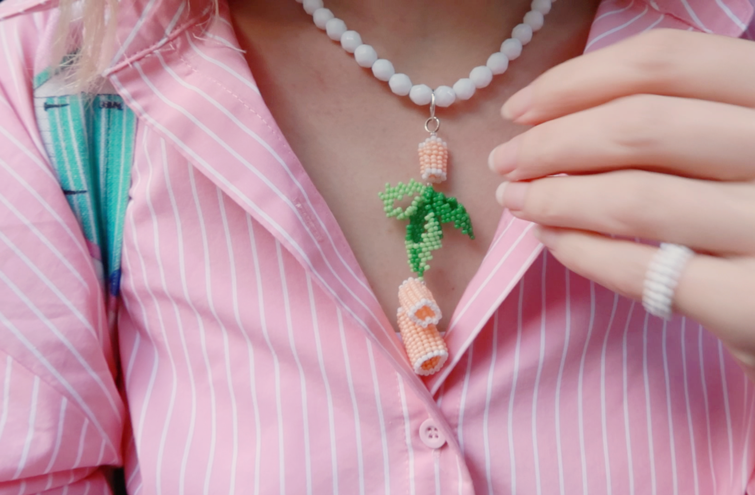 Person wearing a colorful beaded necklace inspired by food with a pink shirt