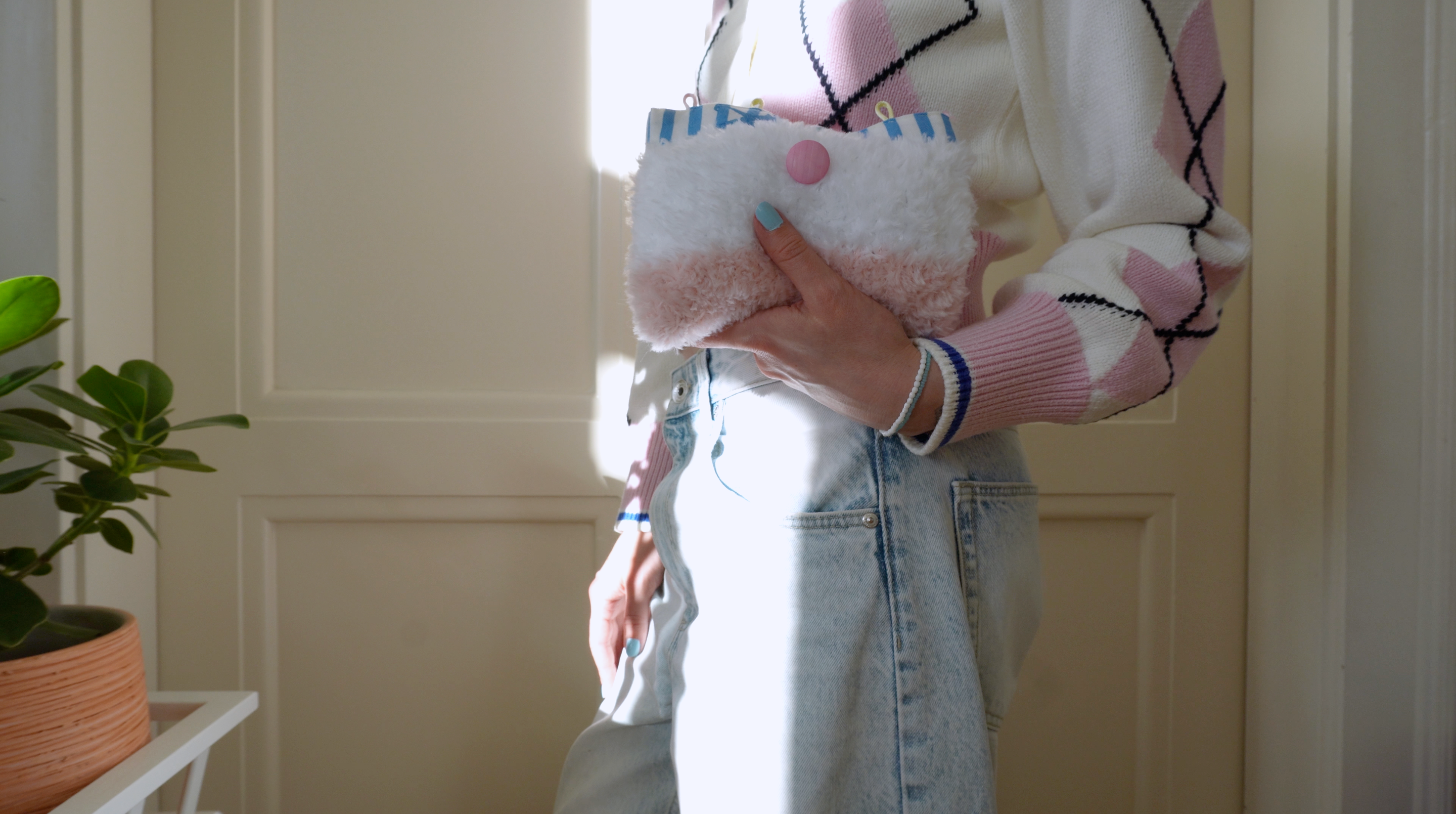Person holding a striped fluffy small handbag with a neutral background
