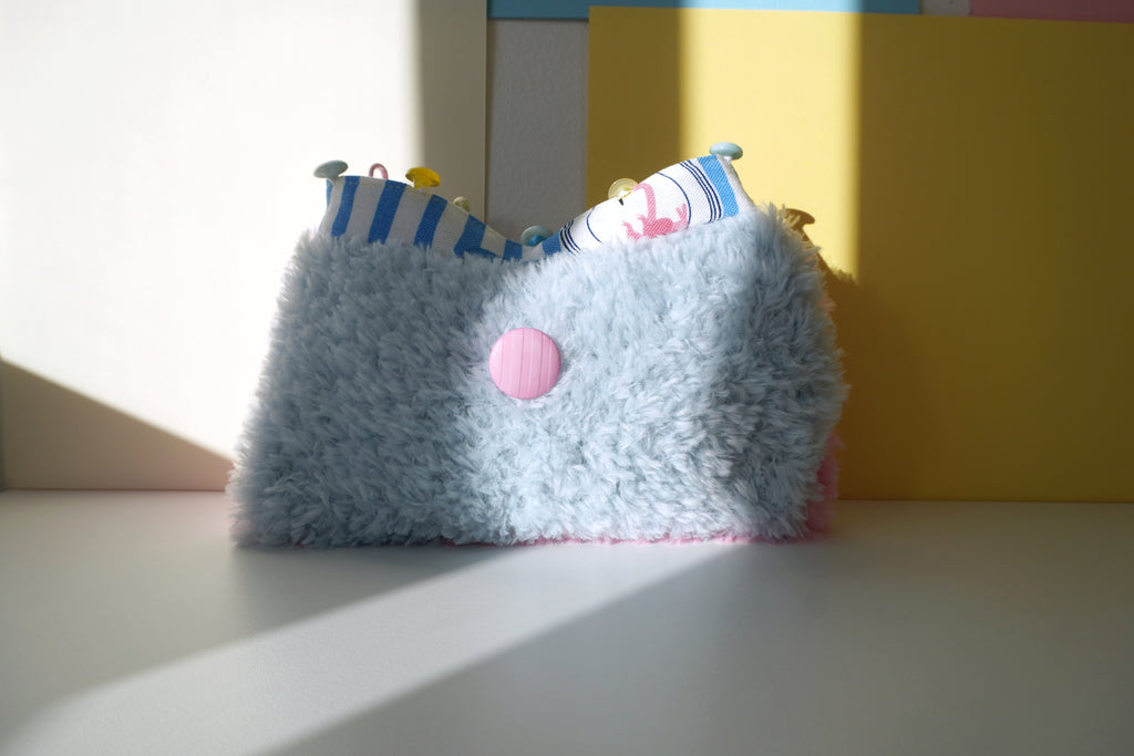 fluffy blue and pink small bag with a striped lining on a light surface