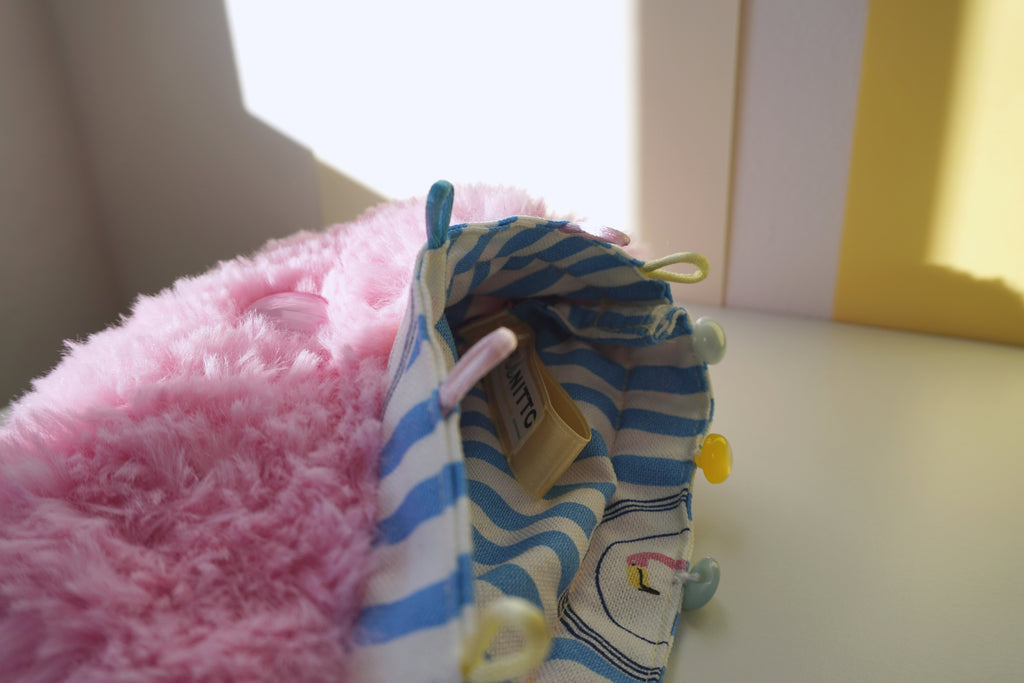 Small fluffy pink bag with blue and white striped lining with a cartoon flamingo and SPOONITTO brand.