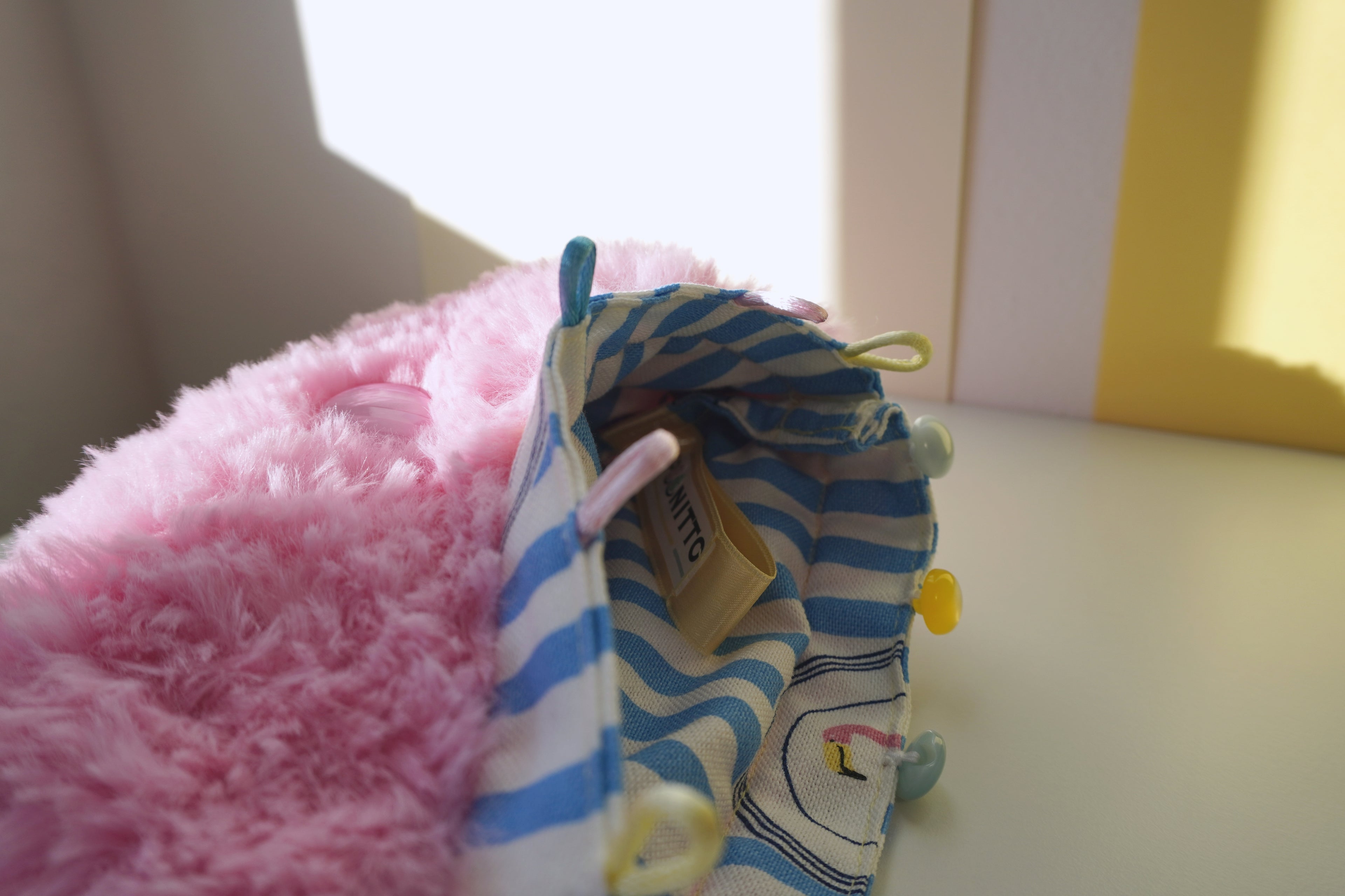 Small fluffy pink bag with blue and white striped lining with a cartoon flamingo and SPOONITTO brand.
