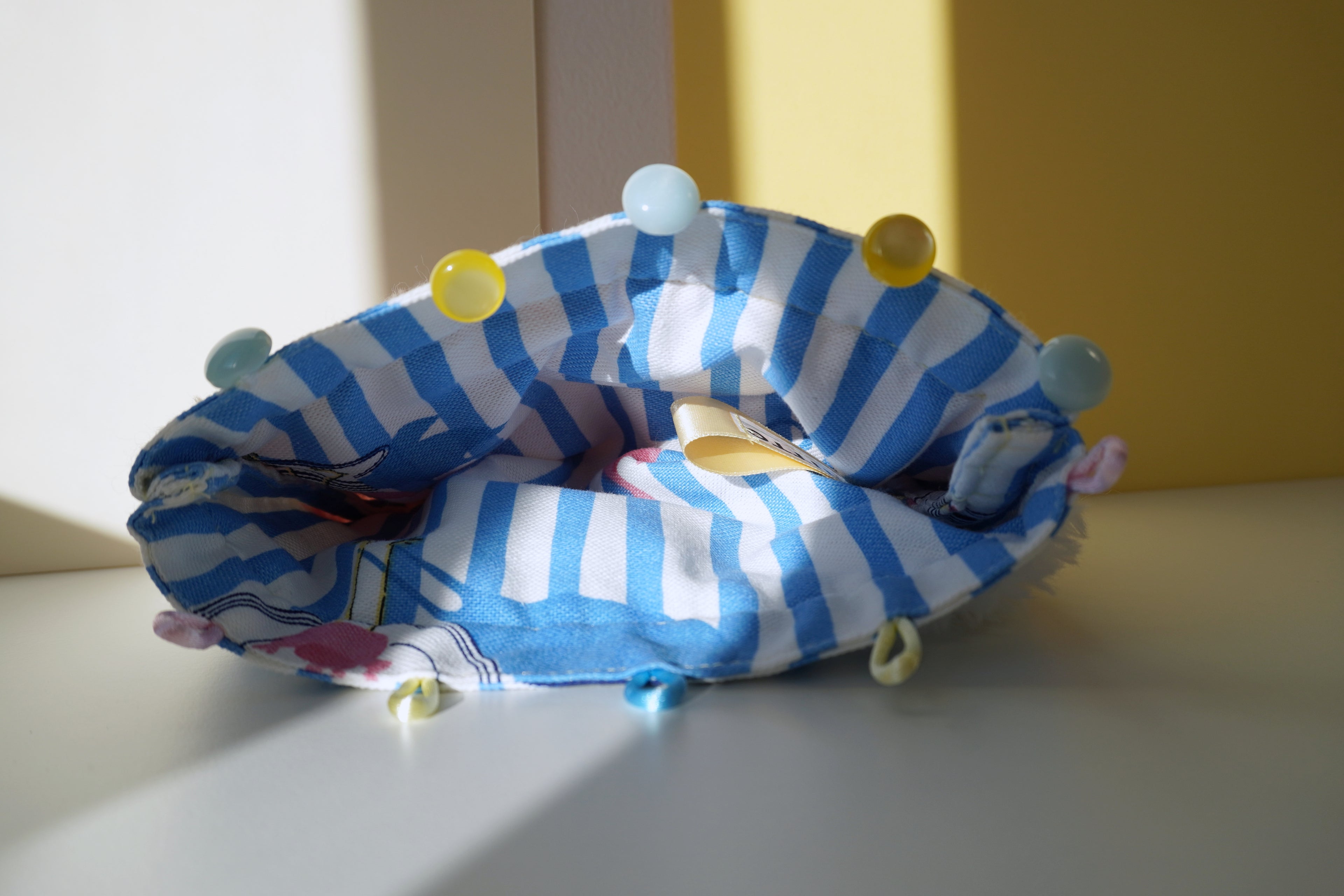 Blue and white striped lining with colorful buttons on a light surface