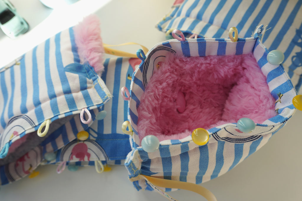 fluffy pink purse with blue and white striped sides on a light background