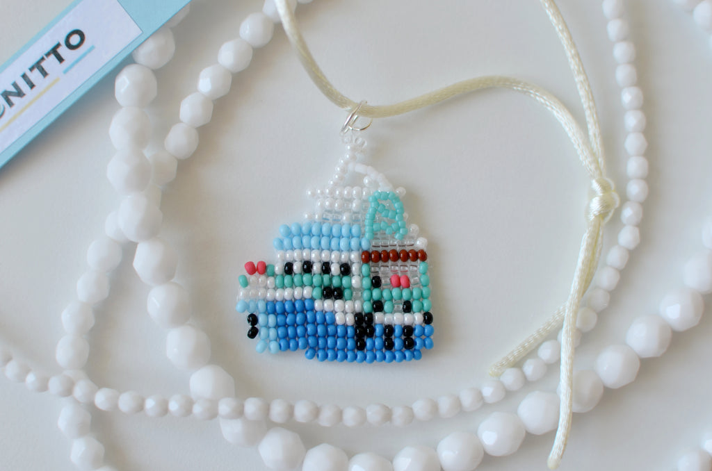 Beaded necklace with a small blue ship pendant on a white background
