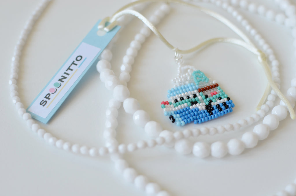 Beaded necklace with a small blue and ship design on a white background